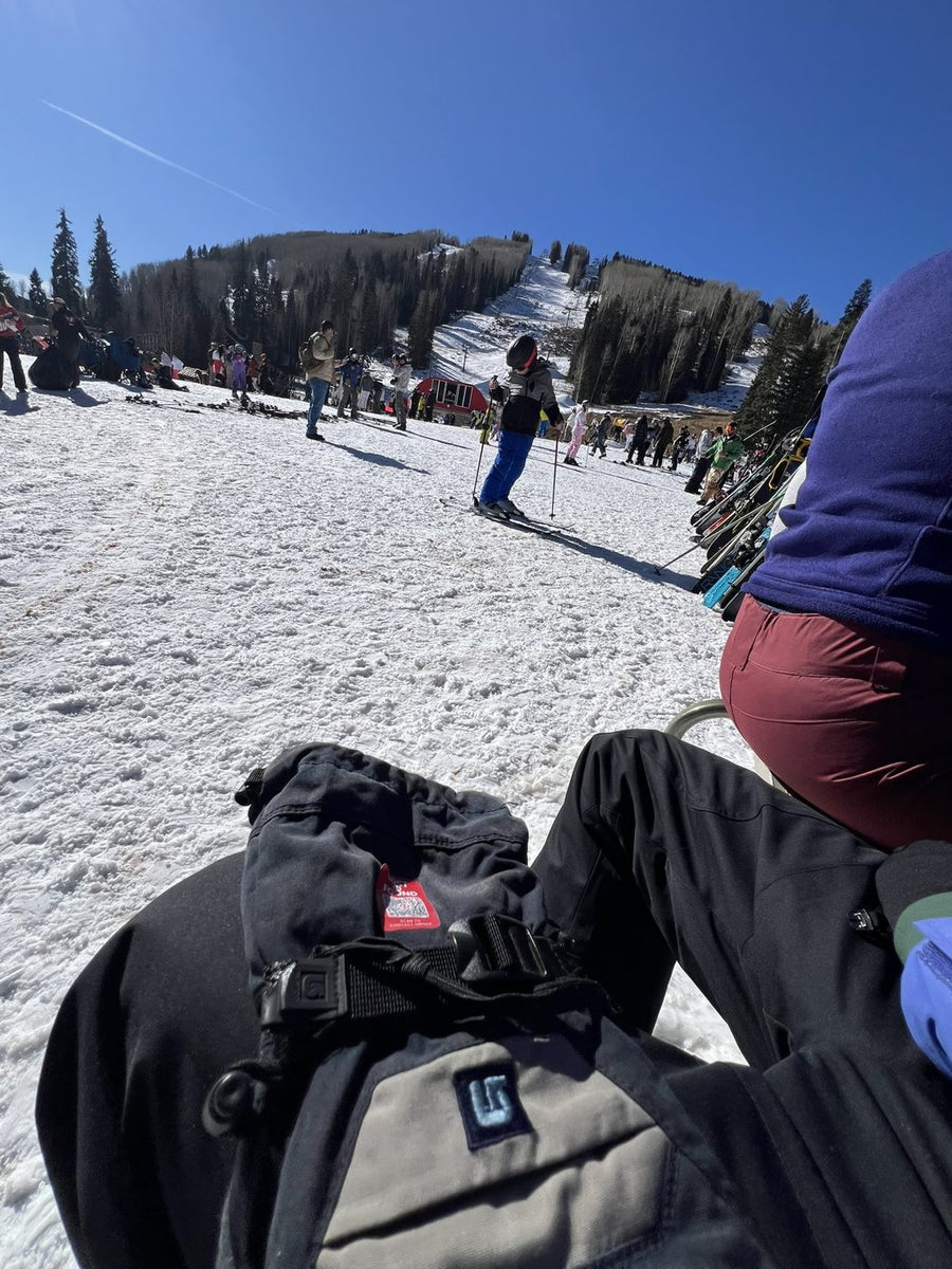 A ski backpack with a Lost N Found return tag, sitting in the snow at the base of the mountain