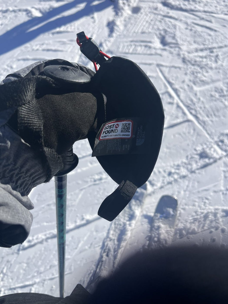 A ski glove liner with a Lost N Found scan to return to owner tag on the inside label
