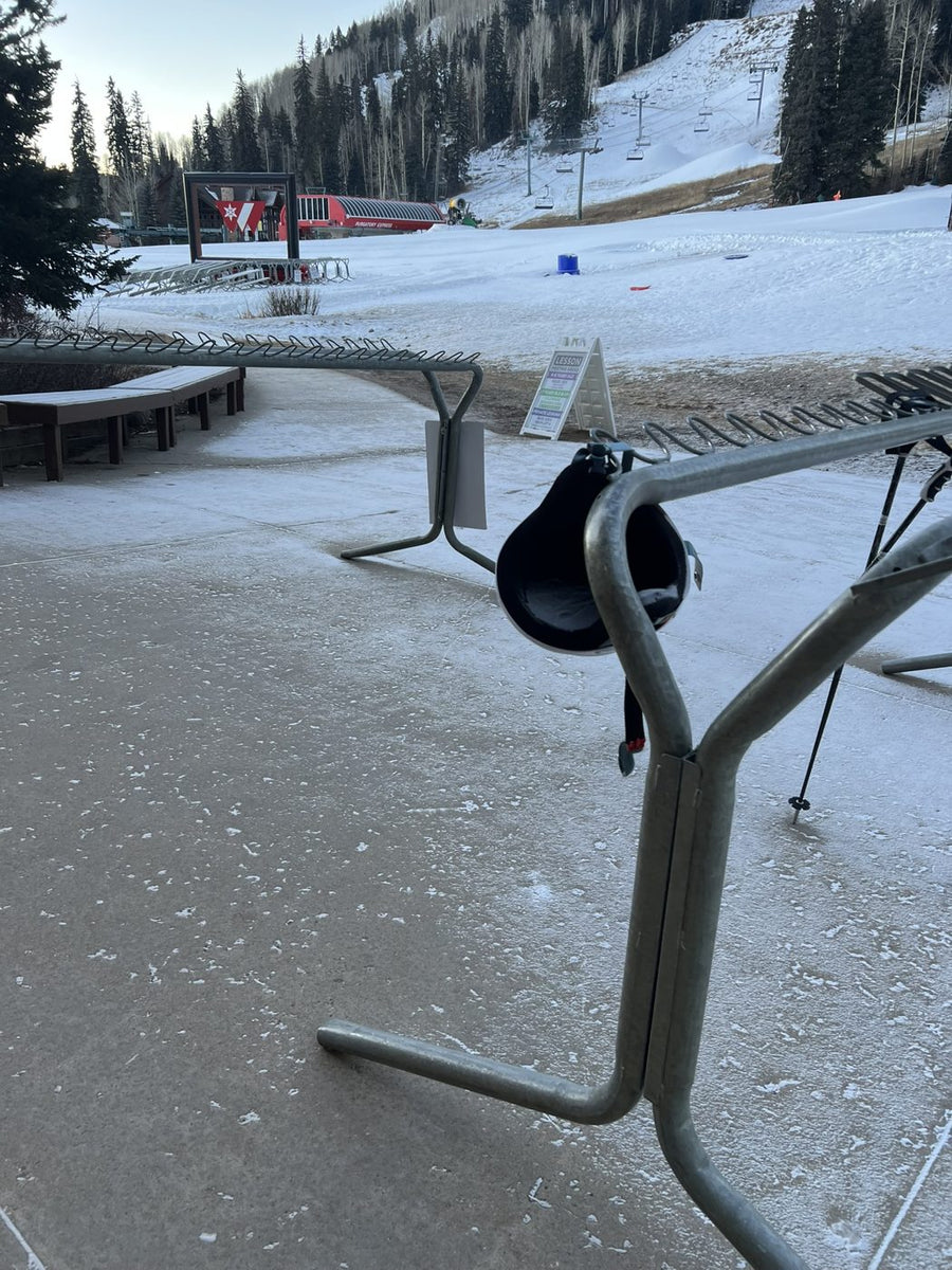 A ski helmet left hanging on an empty ski rack near the lift