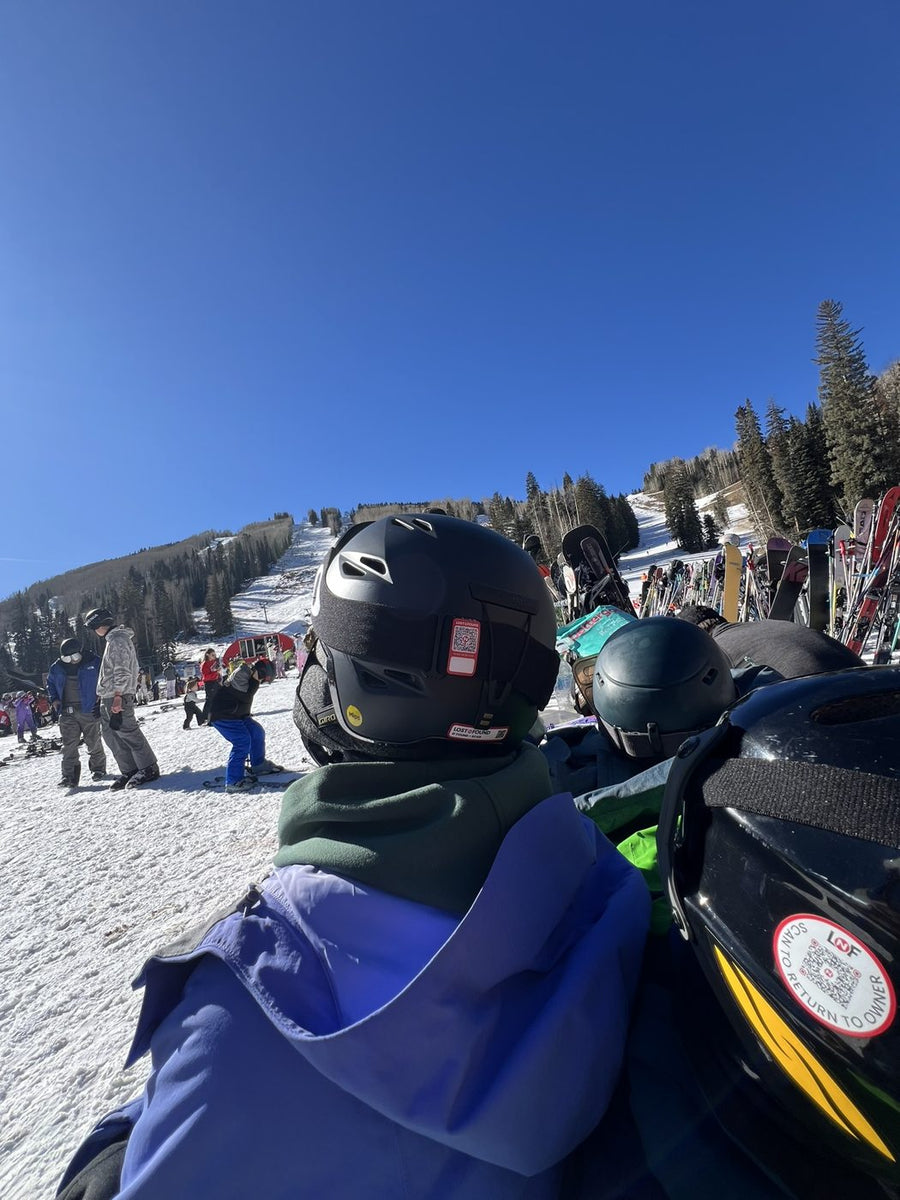 A group of ski helmets in a lift line, each with a Lost N Found scan to return tag